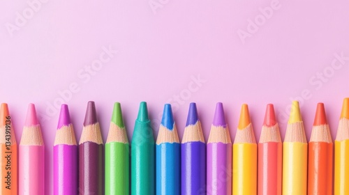 Row of pastel colored pencils on a pink background creates a vibrant pattern