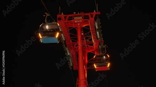 Cable cars over ocean and mountains at night. A series of cable cars cross the ocean, with mountains in the background, creating a breathtaking view. Cabin of cable car 