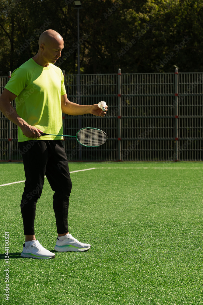 Strong caucasian badminton player racquet hit shuttlecock while practice before competition. Summer sports game, outdoors. Game moment.