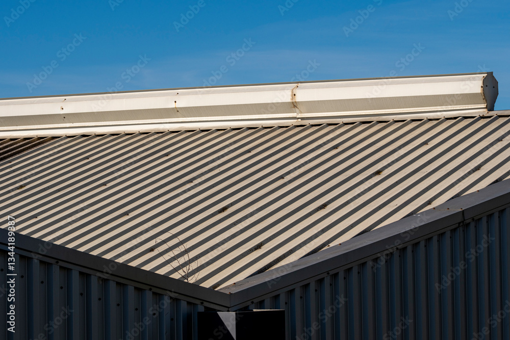 Industrial roof detail with a sharp geometric structure under a blue sky. A minimalistic composition capturing the essence of industrial and modern design. Industrial roof detail with a sharp geometric structure under a blue sky. A minimalistic composition capturing the essence of industrial and modern design.