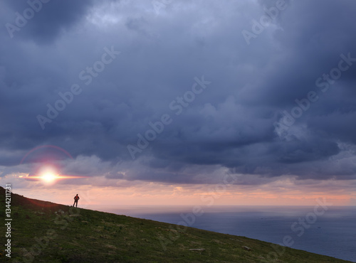 After the storm the sun comes out. Hiker on the Jaizkibel mountain in front of the sea, Basque coast.