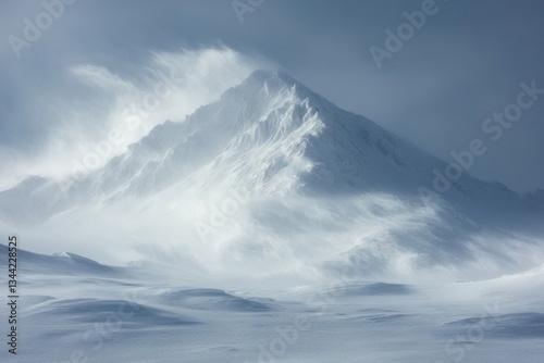 Snowy mountain peak in winter landscape. Wind and snow blowing around summit. Cold weather scene. White and blue tones. Frozen ground with drifts.