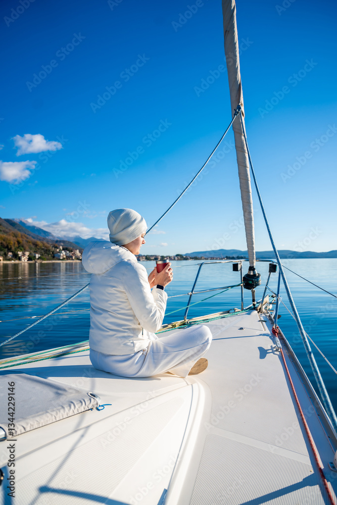 Obraz premium Woman hands holding thermo mug sitting on bow of the yacht during sailing in the morning in winter time in Adriatic sea, relaxation in yachting time