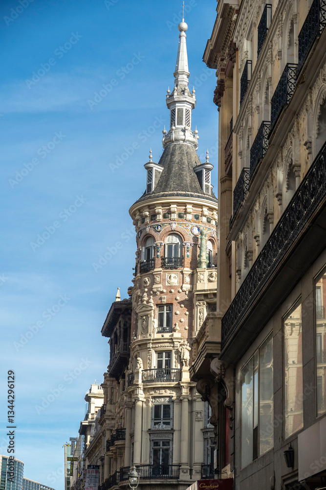 Fototapeta premium A tall building with a steeple is surrounded by other buildings