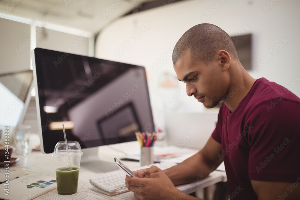 Young man using smartphone at desk in modern office, focusing on work, copy space Young man using smartphone at desk in modern office, focusing on work, copy space