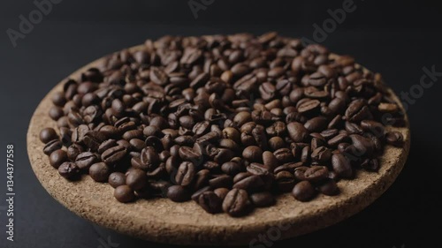 In the shot, black coffee beans on a wooden plate, rotating slowly