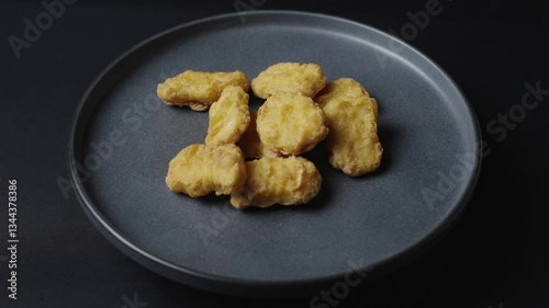 A gray plate is rotating in the frame, chicken nuggets are on the plate. 