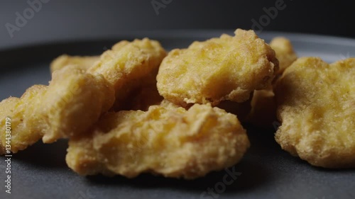 A gray plate is rotating in the frame, chicken nuggets are on the plate. 
