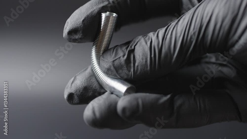 A black glove on the hands , a spring is shown in the hands and how it bends in different directions