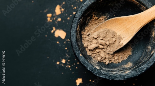 Dark brown powder in a bowl with wooden spoon