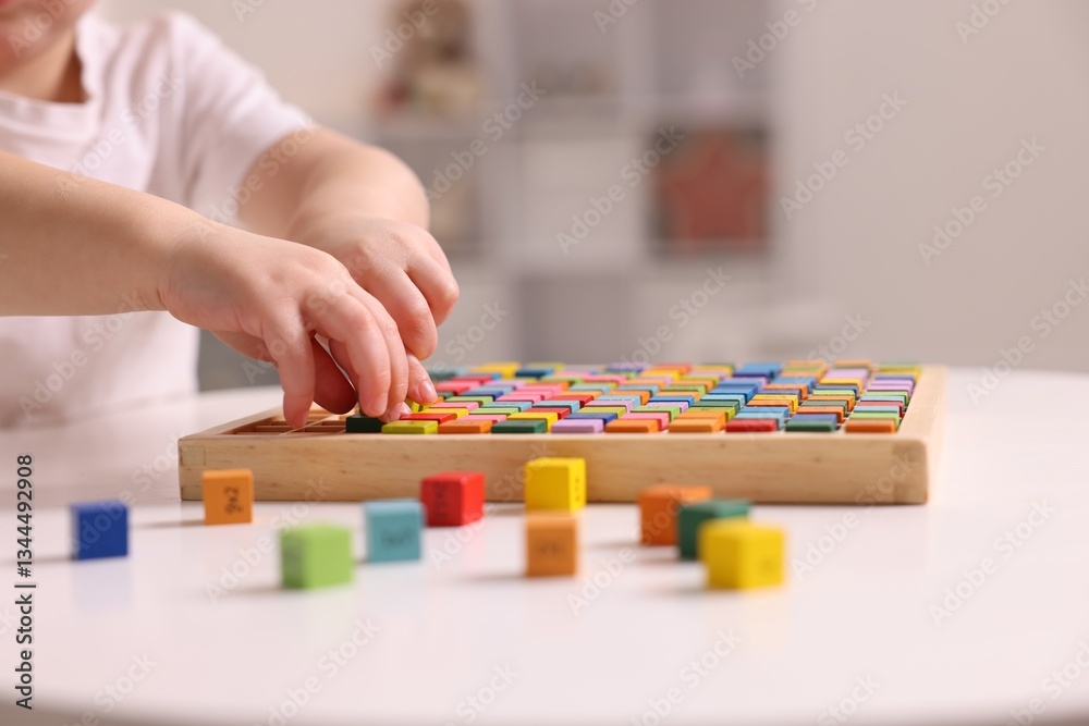 Motor skills development. Little boy playing with Times table tray indoors, closeup Motor skills development. Little boy playing with Times table tray indoors, closeup