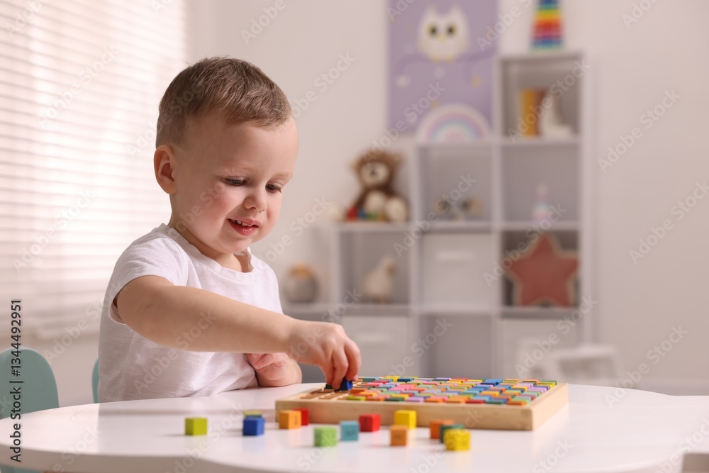 Motor skills development. Little boy playing with Times table tray indoors Motor skills development. Little boy playing with Times table tray indoors