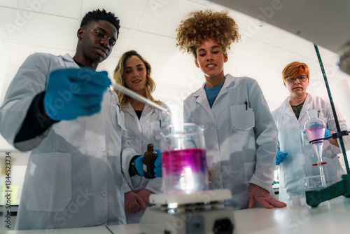 Group of diverse university students and their professor working together, conducting a chemistry experiment in a modern laboratory, mixing colorful chemical solutions