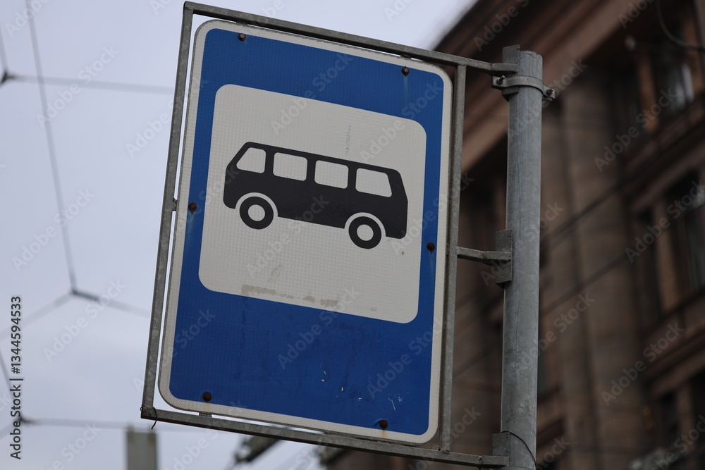 Street sign featuring a blue and white design with a bus passing by.