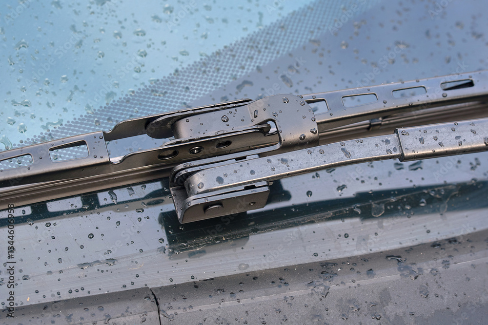 Offset hook wiper arm close-up, wiper blade on wet windshield during rain. Wiper blade with offset adapter for for effective rain and dirt removal, clear visibility and safe driving in rainy weather