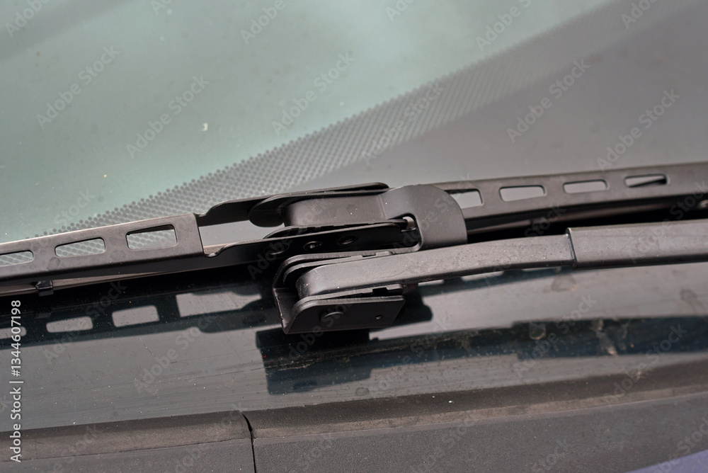 Closeup of black offset adapter mounted on arm of wiper blade for effective rain and dirt removal. Windshield, wiper blade and adapter for optimal visibility during rain and bad weather