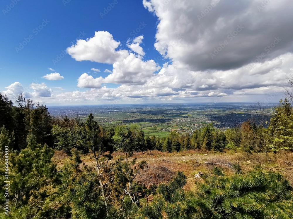 Panoramic view of Beskidy Mountains, Poland, with rolling hills, forests, and villages under a vibrant sky with scattered clouds. Panoramic view of Beskidy Mountains, Poland, with rolling hills, forests, and villages under a vibrant sky with scattered clouds.