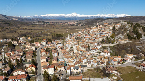 Aerial view of Rocca di Mezzo, a small village on a hill in the province of L'Aquila in Abruzzo, Italy. In the background is the snow-capped Gran Sasso mountain range.