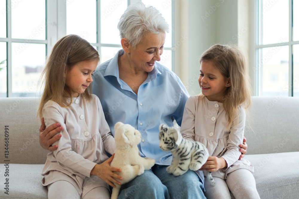 Happy family at home. Two little girls sisters twins grandmother enjoying time together. Good time at home. Grandma granddaughters child kids playing toys hugging together. Family generations Happy family at home. Two little girls sisters twins grandmother enjoying time together. Good time at home. Grandma granddaughters child kids playing toys hugging together. Family generations