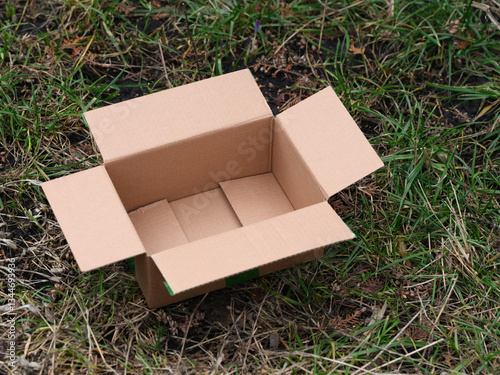An empty cardboard box lying on grass outside. Close up.