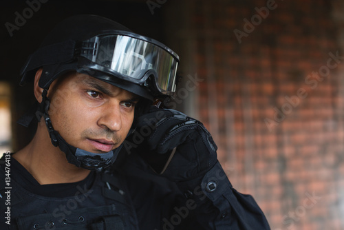 Tactical officer in black gear communicating through earpiece, focused on mission, copy space photo