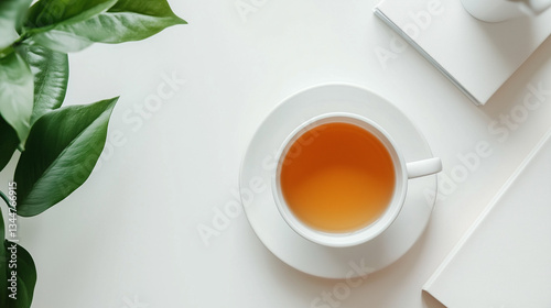 Minimalist office setup with a white desk, simple accessories, and calming tea, white cup with green tea leaves, top view. 