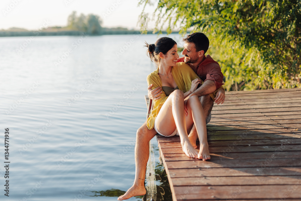Fototapeta premium Happy couple relaxing and enjoying a romantic sunset on a lake pier