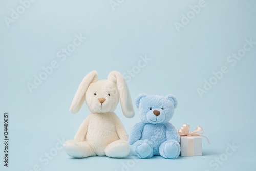 Soft plush toys blue bear and white bunny with gift box, blue studio wall, copy space