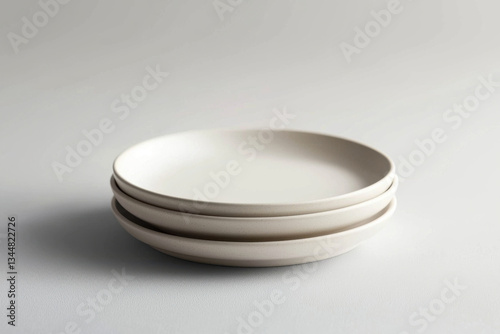 Minimalist design highlights three elegant white plates stacked quietly on a textured surface, evoking simplicity and sophistication in contemporary dining