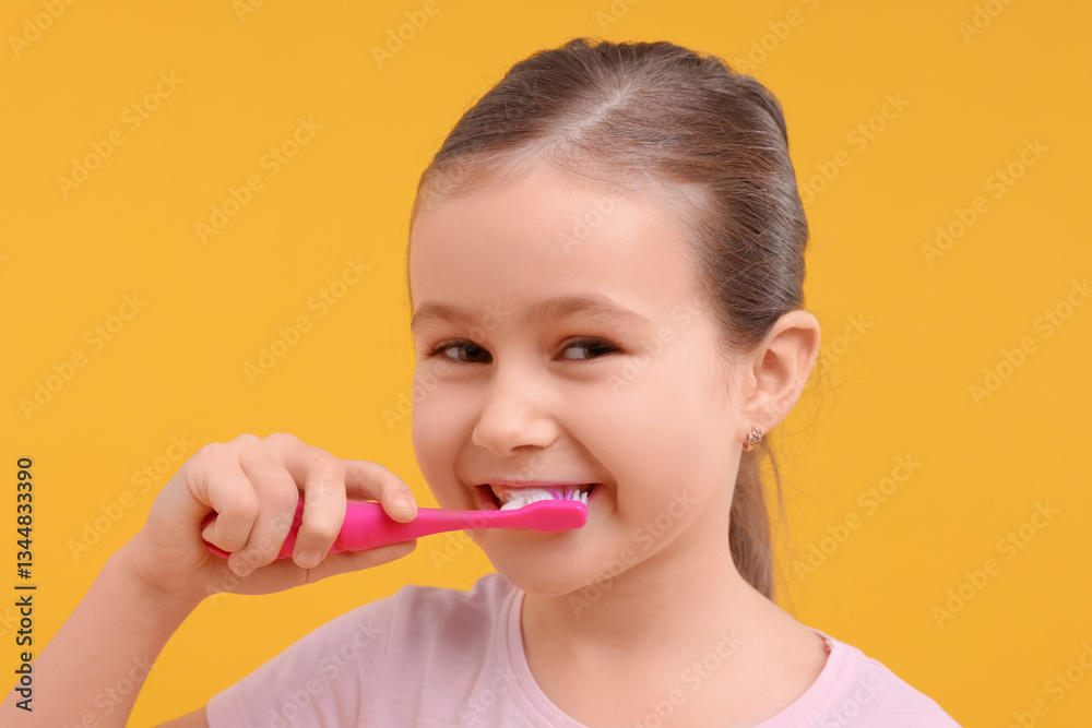 Cute girl brushing her teeth on orange background Cute girl brushing her teeth on orange background