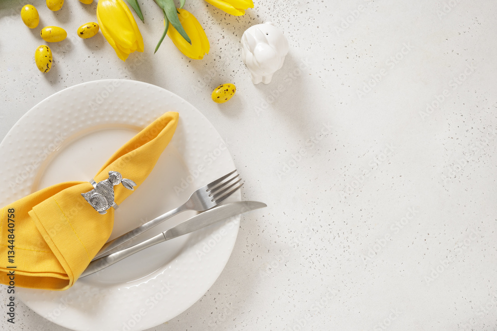 Easter table setting with spring, yellow tulips, white plates, bunny, eggs on white background. Happy Easter celebration. Copy space. Top view.