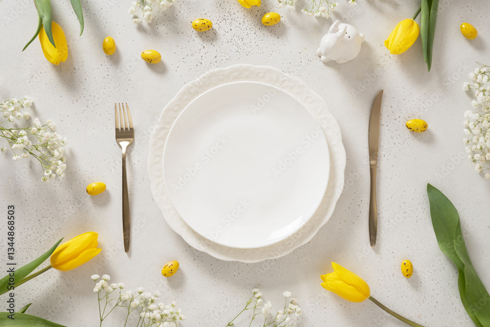 Easter table setting with spring, yellow tulips, empty white plates, bunny, eggs on white background. Happy Easter celebration. Copy space. View from above.