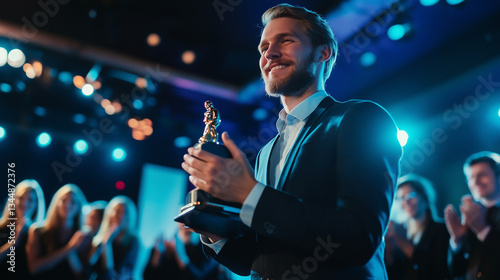 Employee receiving an award on stage with colleagues applauding in the background.