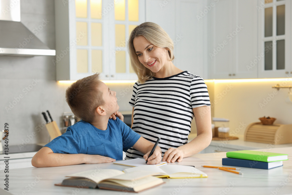 Mother and son doing homework at table indoors Mother and son doing homework at table indoors