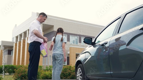 caring father by car sees child kid girl daughter school, happy family, school building background, father helps child kid girl daughter put backpack, girl with school backpack goes school, man father