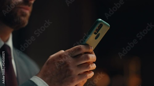 Manager hand texting cellphone screen answering email at night office closeup