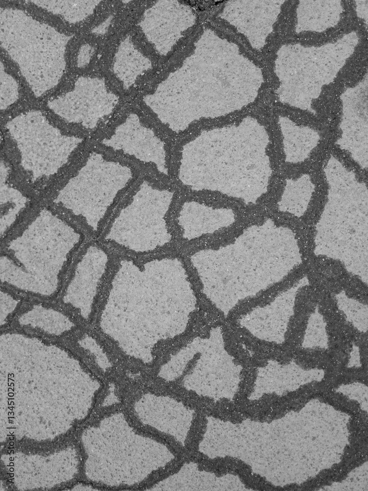 Cracked asphalt surface with irregular patterns. Black and white close-up. Cracked asphalt surface with irregular patterns. Black and white close-up.