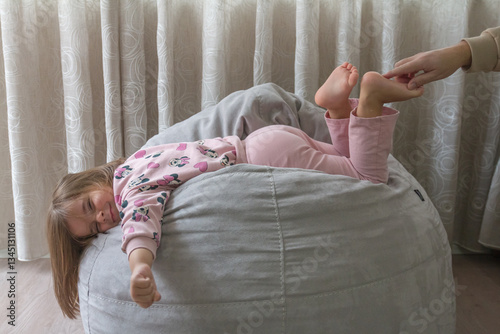 little girl trying not to laugh at her father's tickling of her leg,family and love concept