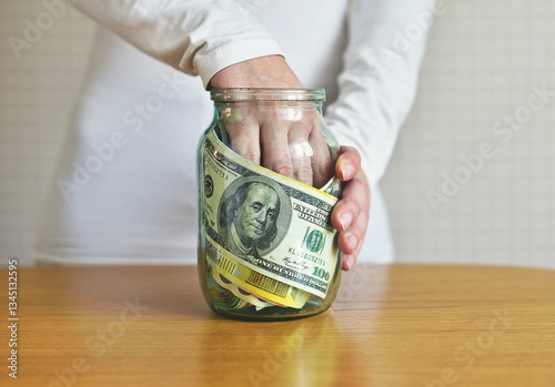 Conceptual Photo of Hand Reaching for Money in a Jar