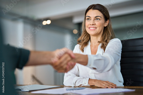 Happy professional mid aged business woman manager handshaking at office meeting. Smiling female hr hiring recruit at job interview, bank or insurance agent, lawyer making deal with client at work.