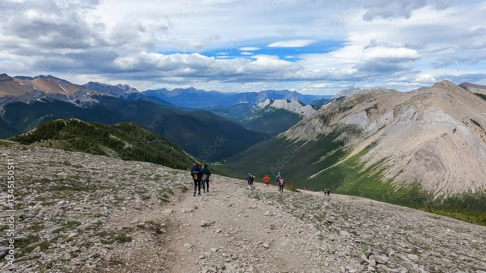Hiking the mountains in summer, people with backpacks enjoy nature, landscapes, and adventure in panoramic mountains view—a true outdoor travel and touris experience in the endless peaks of The Rocky. Hiking the mountains in summer, people with backpacks enjoy nature, landscapes, and adventure in panoramic mountains view—a true outdoor travel and touris experience in the endless peaks of The Rocky.