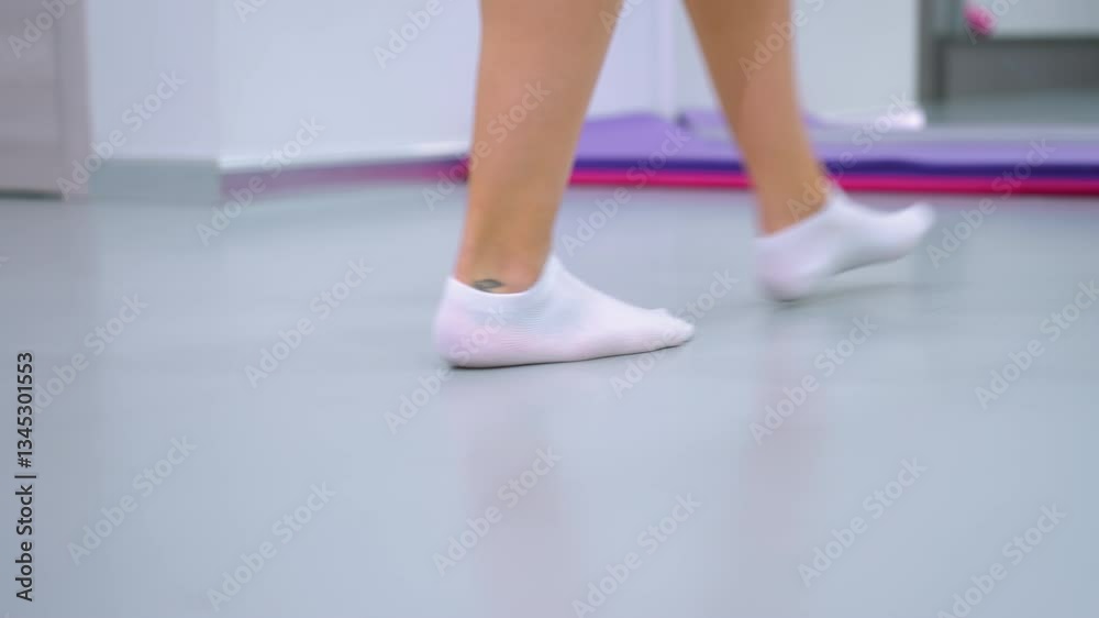 Close-up of lower legs in white ankle socks walking toward yoga mat in modern fitness studio, mirror reflects surroundings as person drags mat, background features workout equipment Close-up of lower legs in white ankle socks walking toward yoga mat in modern fitness studio, mirror reflects surroundings as person drags mat, background features workout equipment
