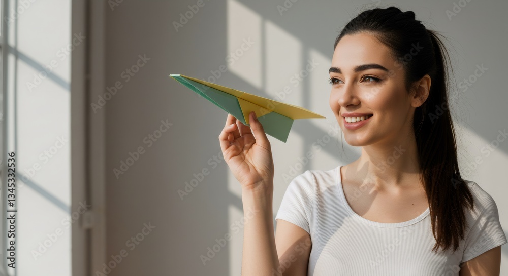 Woman holding green paper airplane in sunlit room. Travel dreams and aspirations concept. Wanderlust and adventure planning. Playful indoor activity for vacation inspiration. Woman holding green paper airplane in sunlit room. Travel dreams and aspirations concept. Wanderlust and adventure planning. Playful indoor activity for vacation inspiration.
