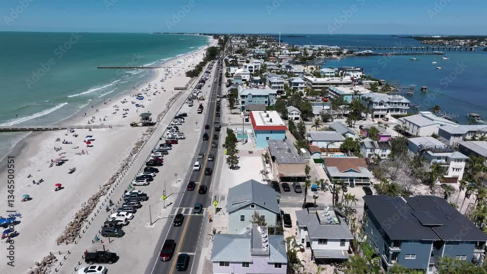 Traffic scene at Main Street of Bradenton Town during sunny day. People and tourist relaxing at sans beach with clear water. Housing area and neighborhood in summer. Aerial lateral wide shot. FL, USA.