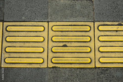 Yellow tactile paving in Jakarta City sidewalks, the function is for assisting visually impaired pedestrian while walking, suitable for background and texture resources