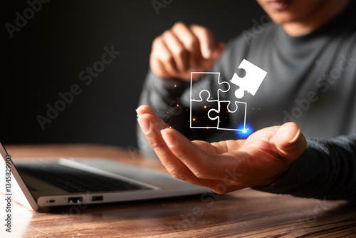 Businessman using laptop with jigsaw icons for problem solving concept and leadership strategy, success in intellectual problem solving.