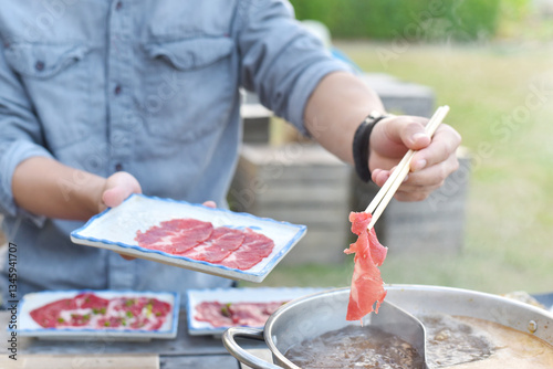 close up of chopstick Holding beef in a shabu-shabu dish