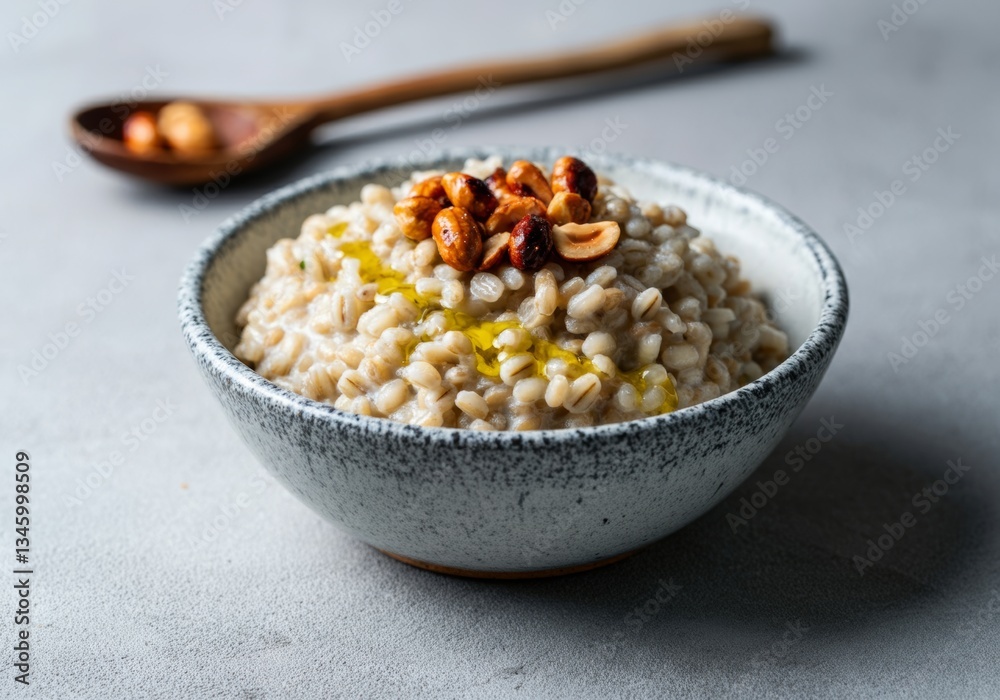 Creamy barley risotto with roasted hazelnuts in ceramic bowl on gray surface Creamy barley risotto with roasted hazelnuts in ceramic bowl on gray surface