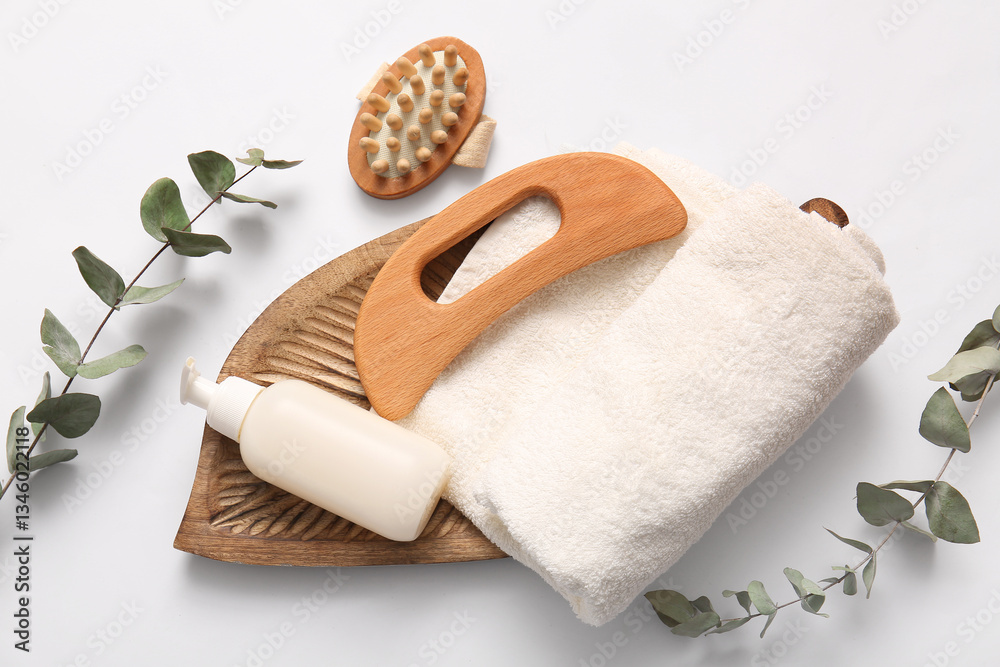 Fototapeta premium Guasha body massage tool, wooden tray, bottle of serum, towel, head brush and eucalyptus twigs on white background