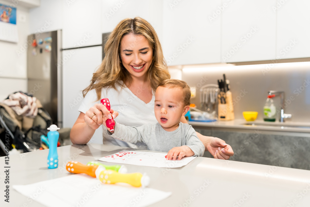 Happy mother helping baby boy drawing with dot markers at home Happy mother helping baby boy drawing with dot markers at home